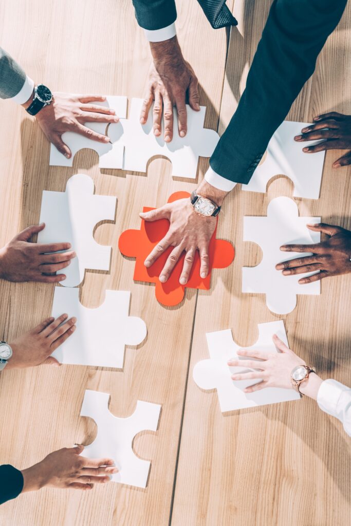 overhead view of multiracial businesspeople assembling puzzle on table